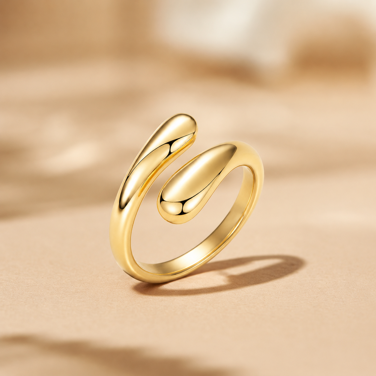 A Elnovaire polished gold ring with a modern, fluid, open spiral design, standing upright on a textured beige surface with a soft-focus background.