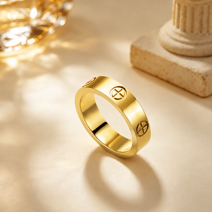 A Elnovaire polished gold ring with engraved cross symbols on its outer band, displayed on a warm beige surface with soft shadows and decorative classical props in the background.